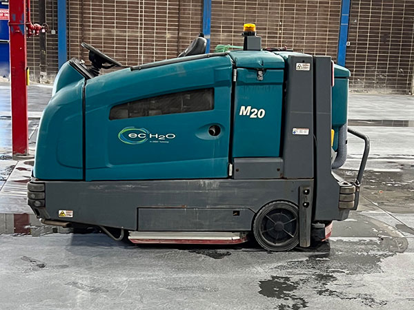 A floor scrubber sits on a warehouse floor.